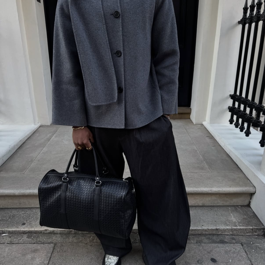 sober gray and black outfit coat and pants and man bag the man is wearing monateo jewelry