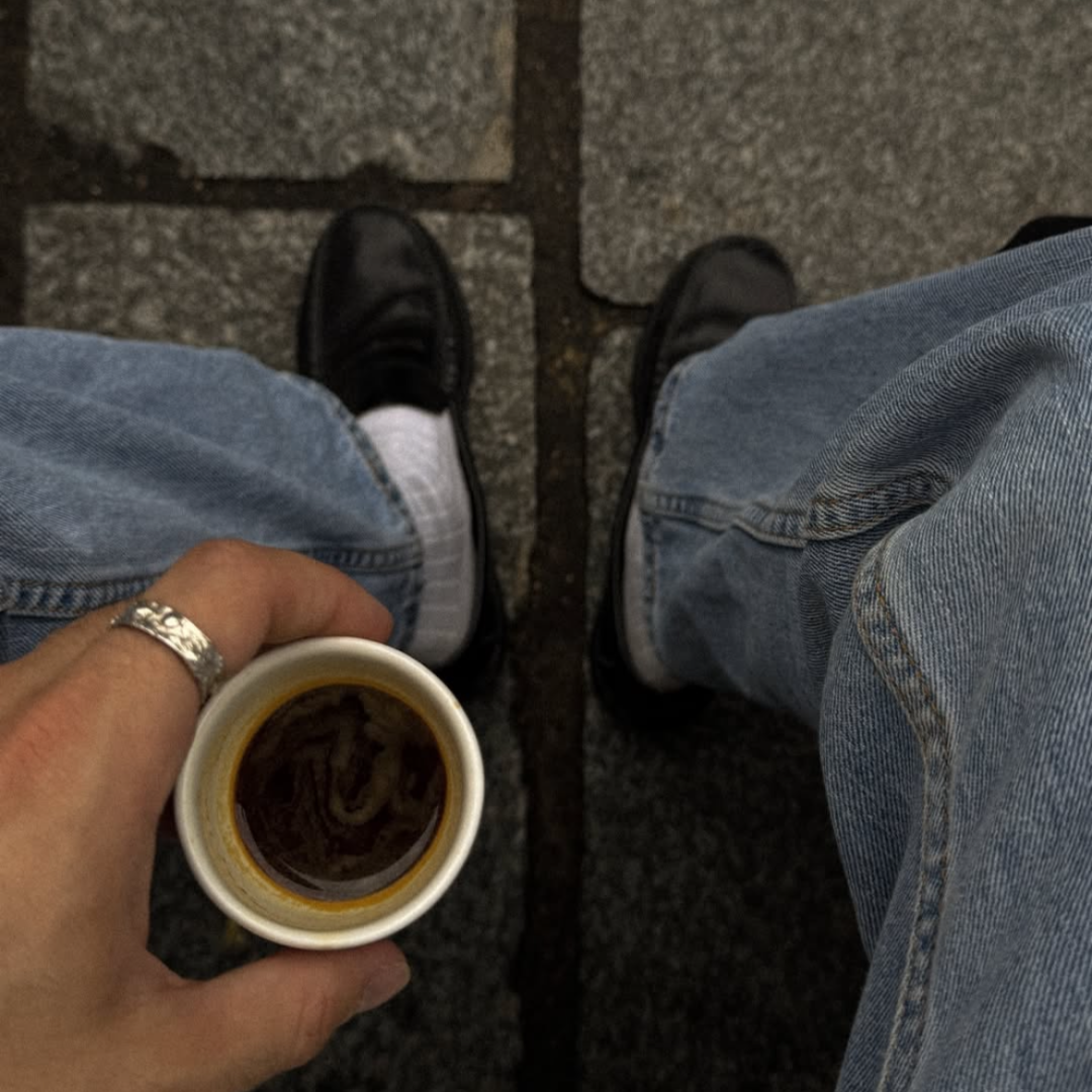 a hand holding a cup of coffee and wearing monateo ring
