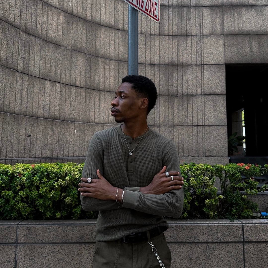 stand up black man wearing monateo jewelry, necklace, rings. cross arm pose.